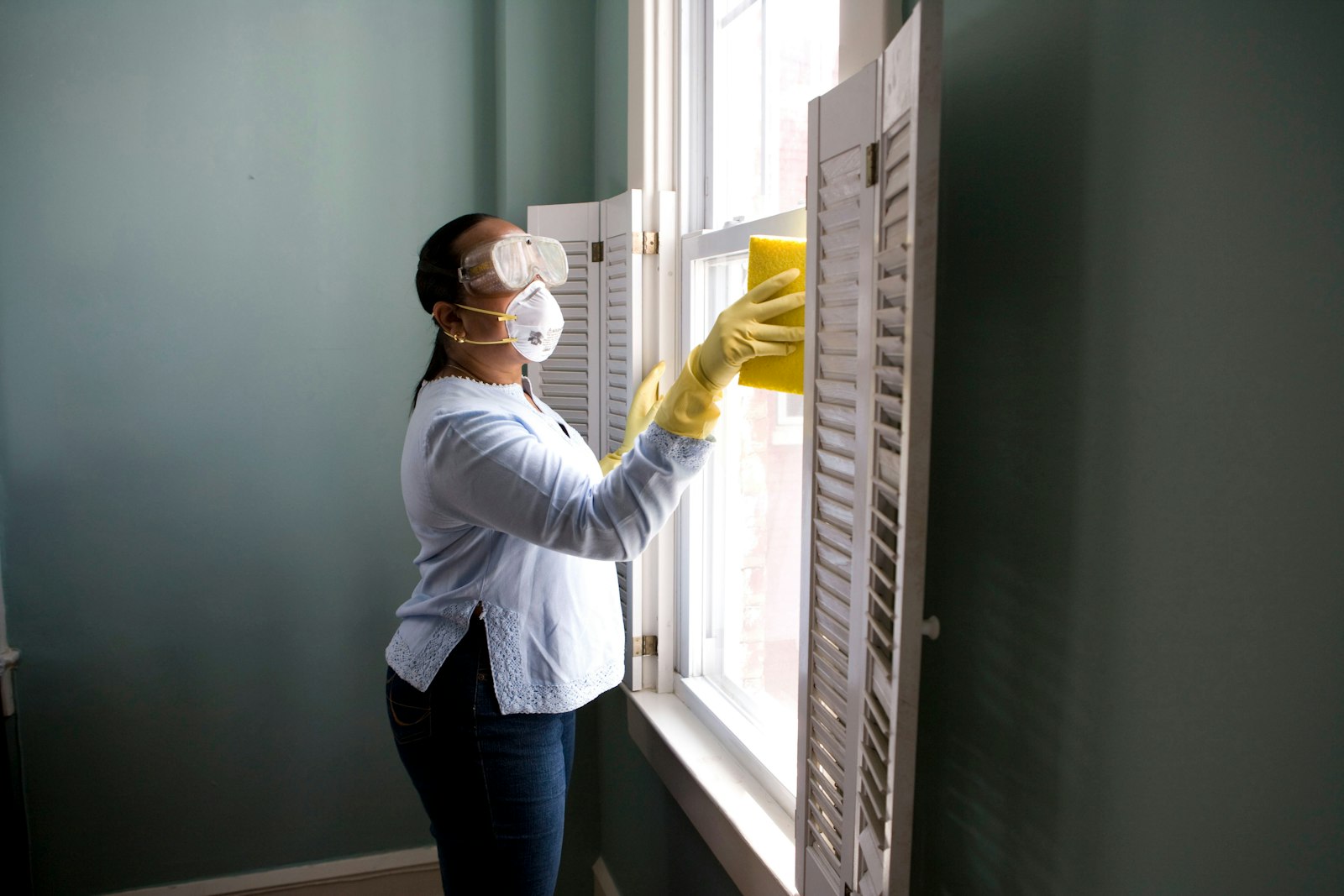 Cleaner in protective equipment cleaning windows in an empty new property