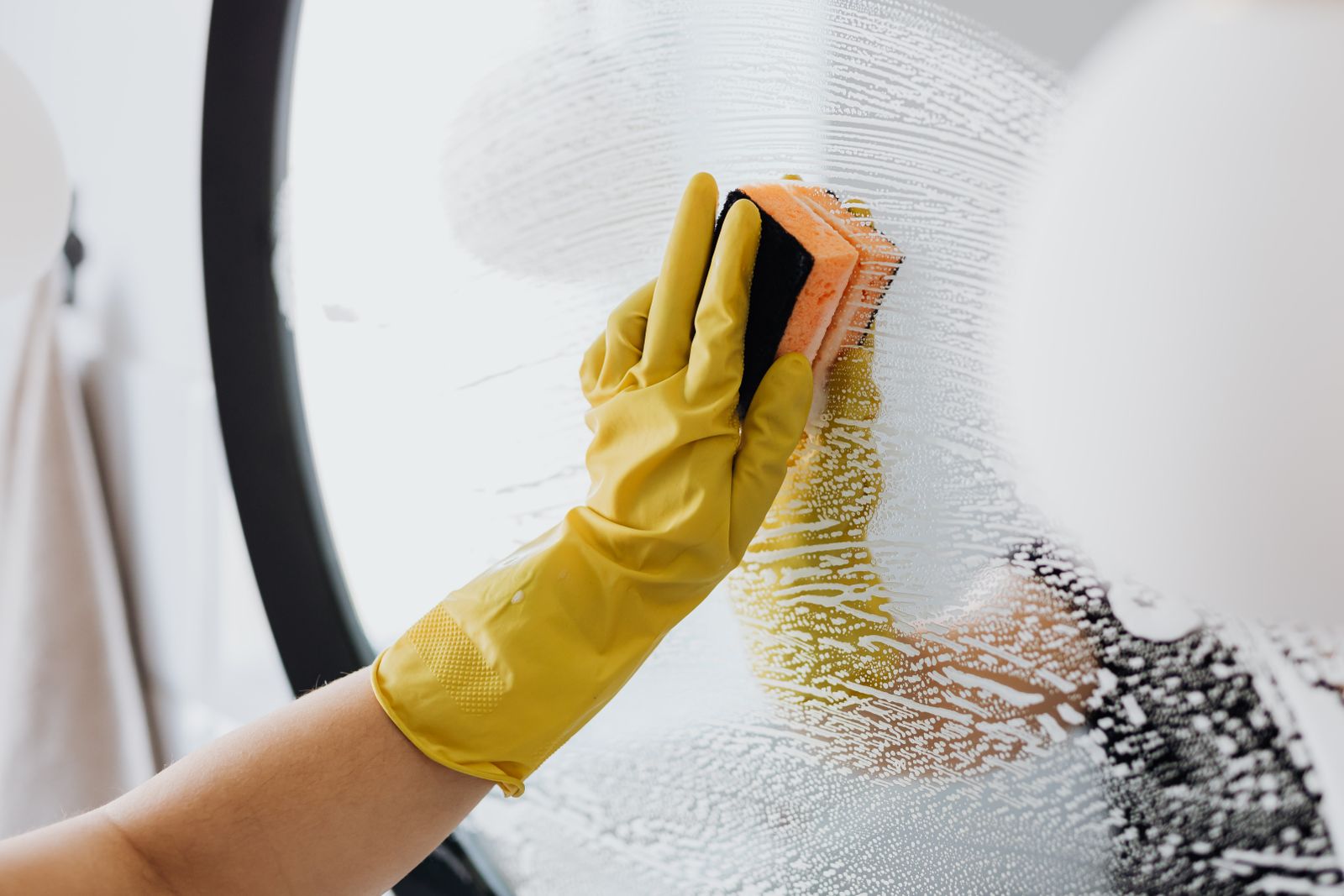 Professional cleaner washing communal glass with foam
